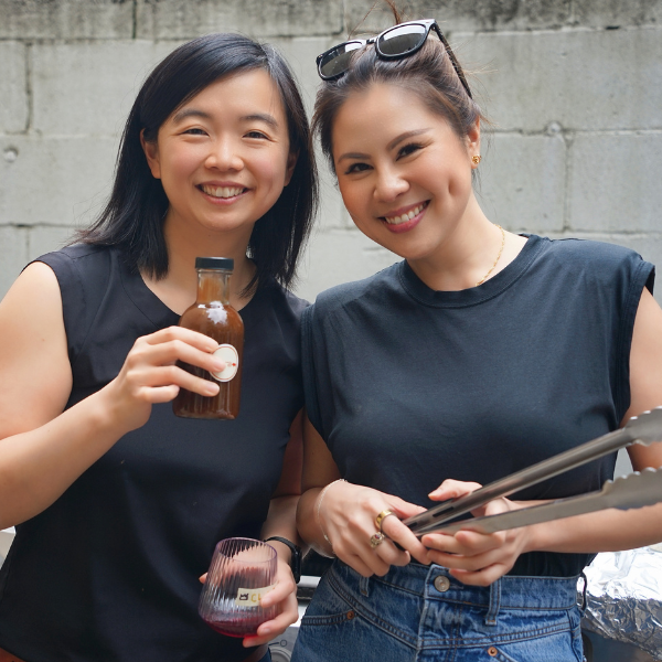 Flora and Clara, the founders of chara, holding sauce and grilling tools